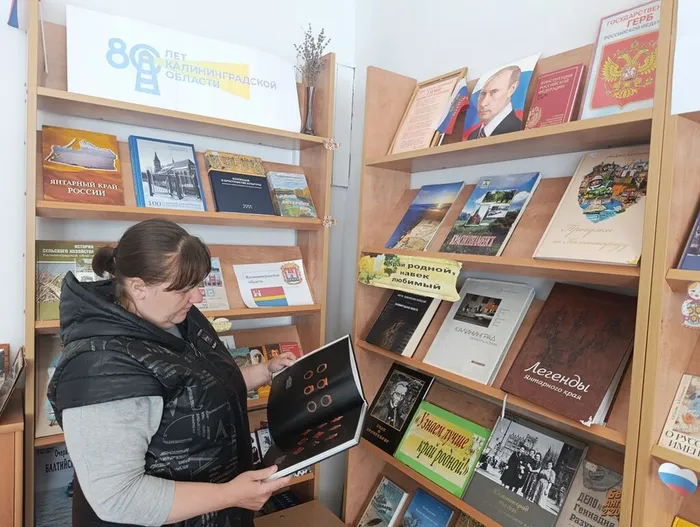 Молоткова Е. рассматривает книгу Янтарь в природе и искусстве