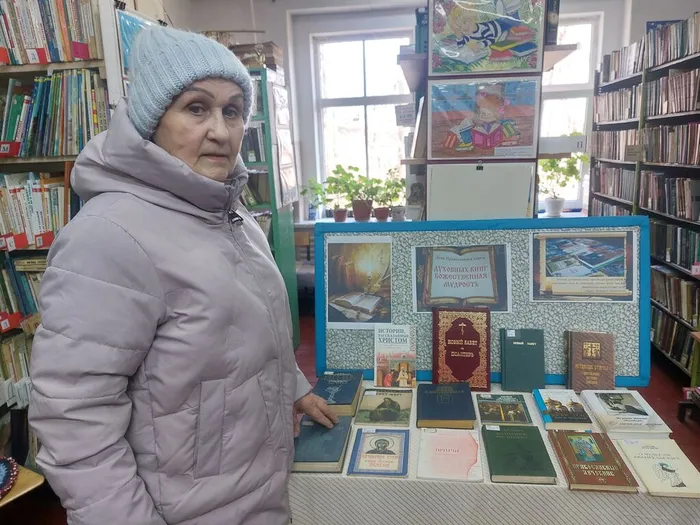 На фотографии читатель библиотеки у книжной выставки, посвящённой православной книге