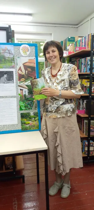 на фотографии библиотекарь преставляет книгу юбиляра Истории замланского лесника