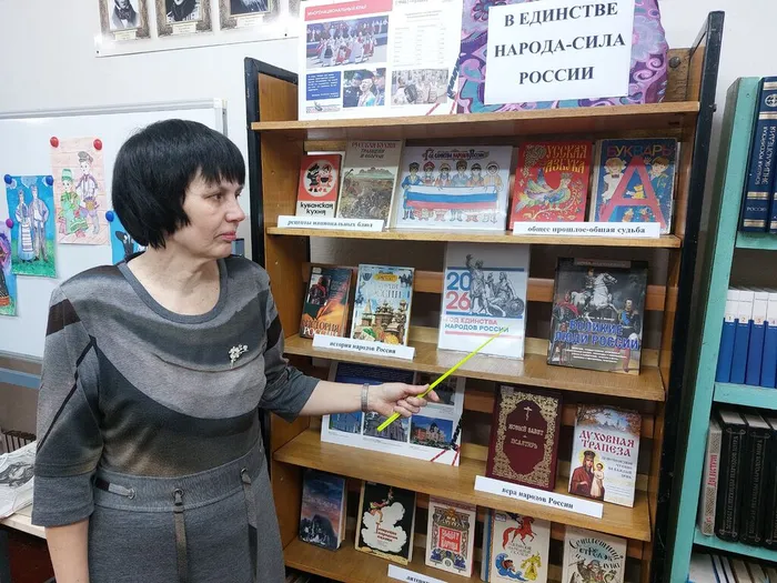 На фотографии библиотекарь представляет книжную выставку В единстве народа - сила России