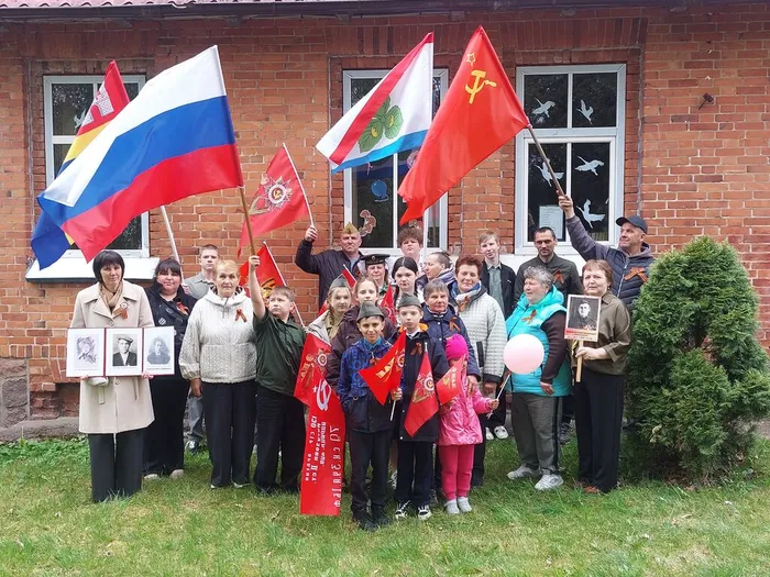 На фотографии Общее фото односельчан с портретами ветеранов