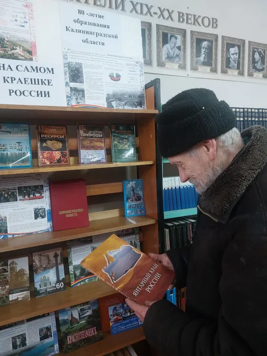 На фотографии Валавичус Л.П. знакомится с художественнымальбомом Янтарный край России
