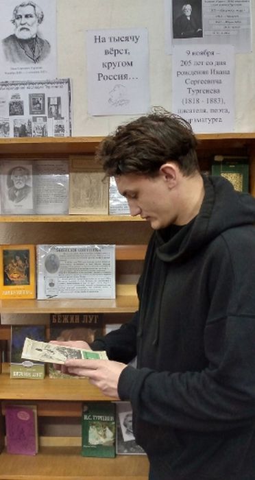на фотографии читатель Неманской библиотеки осматривает экспонаты книжной выставки